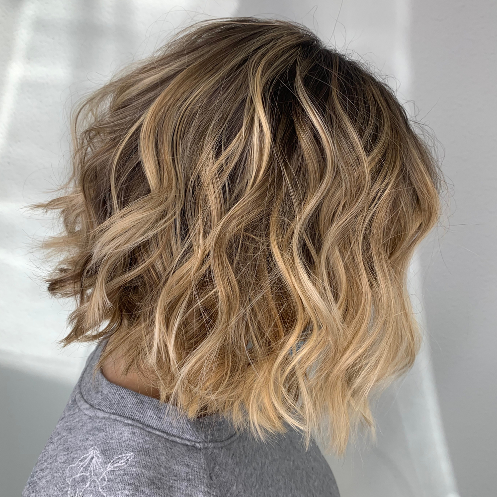 Side view of blonde wavy bob to show an example of low maintenance medium length hairstyles for thick hair