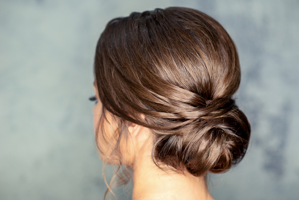 Back side view of a fancy chignon hairstyle that works well for long straight hair seen on a brunette woman