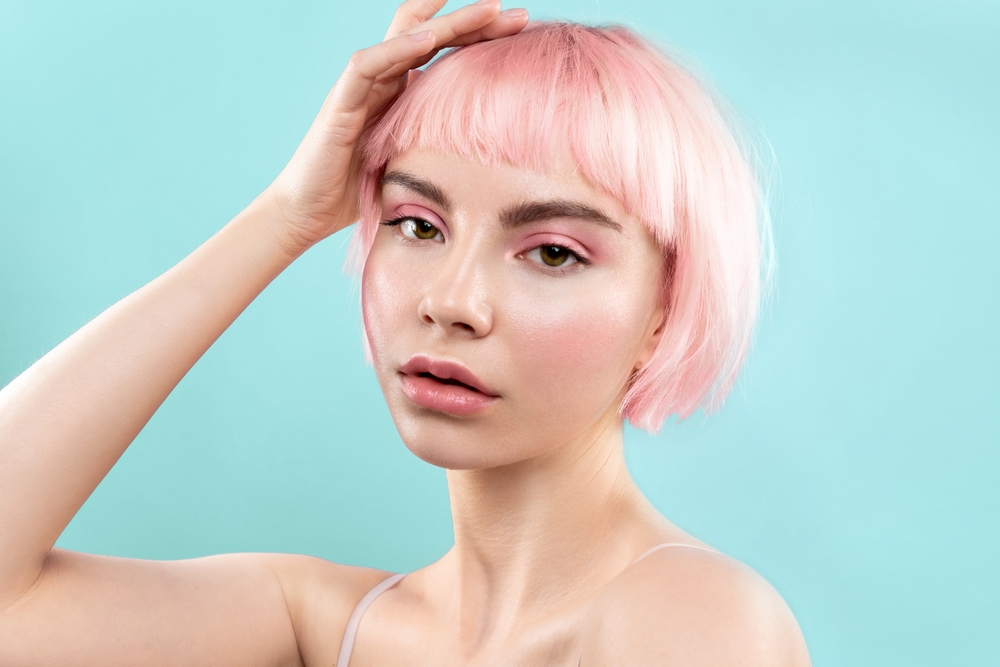 Young woman with pink bob haircut and bangs shows the concept of fine hair thin hair low maintenance short hairstyles that make hair look thicker
