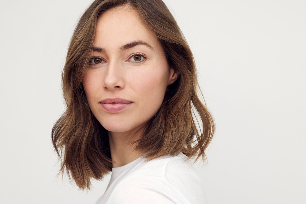 Brunette woman looks over her shoulder with a layered lob, one of the most popular low maintenance haircuts for women