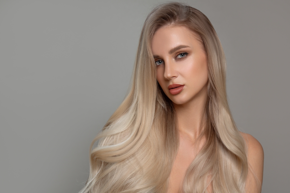 Woman looks serious modeling a long hairstyle with a side part and curled ends