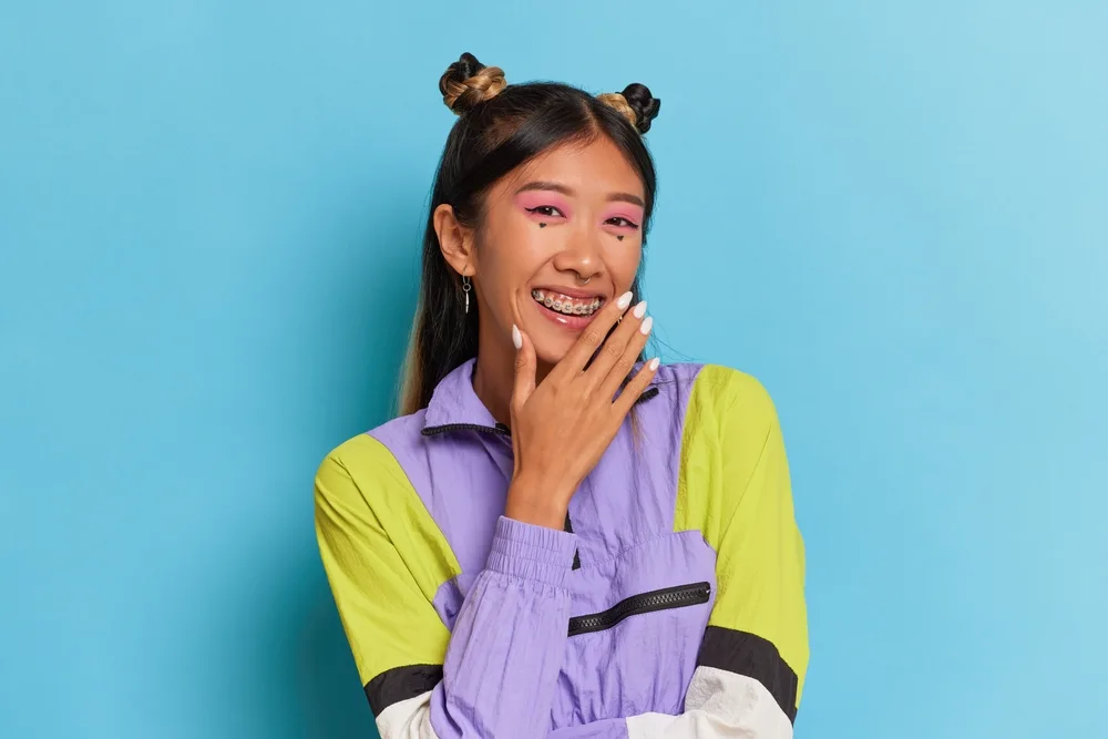 Young Asian woman smiles with braces wearing a half up braided space bun look to show hairstyles for long straight hair