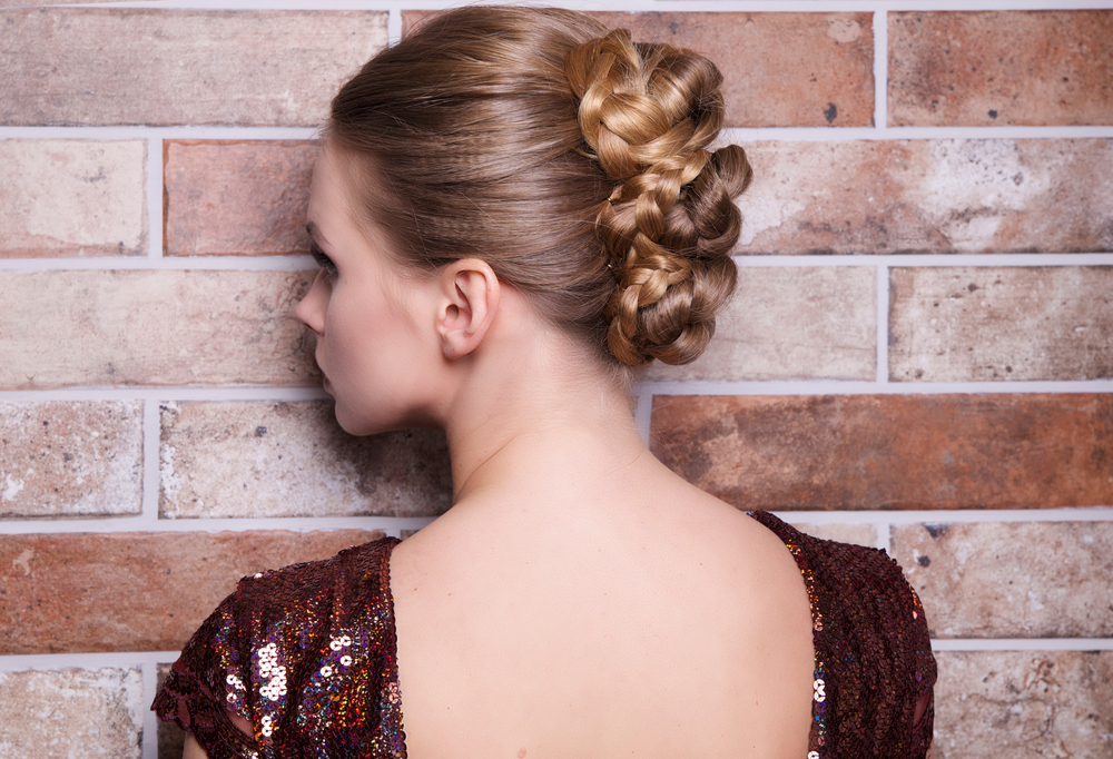 Back view of woman in an open back dress wearing a braided updo as an example of cute homecoming hairstyles