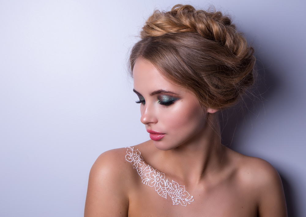 Young woman with a white henna tattoo on her collarbone sports one of the trendiest homecoming hairstyles with a rope crown braid